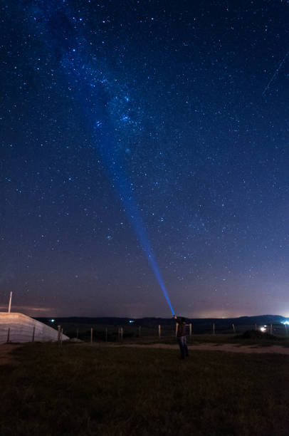 istock milky way sky with a silhouette man flashing a lantern to the sky 1219743614
