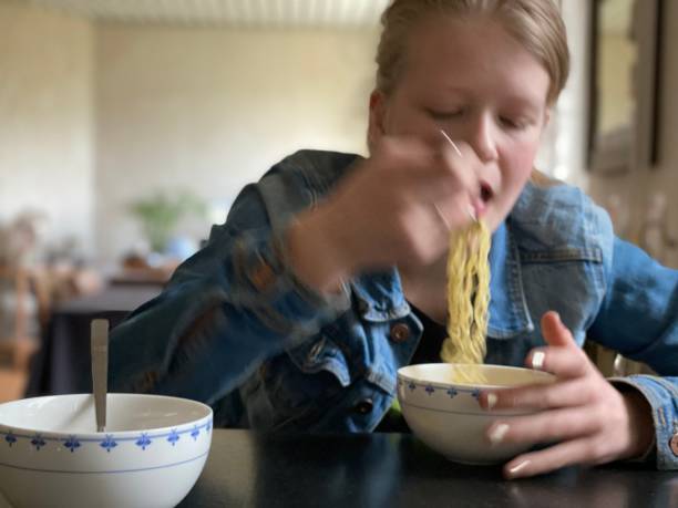 istock Girl eating noodles 1219747036