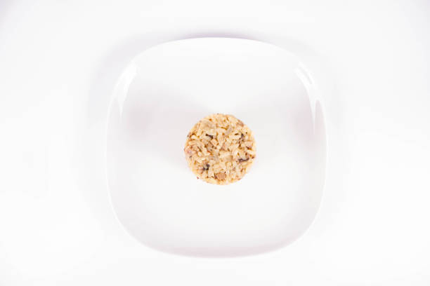 Risotto with button mushroom and bacon on a plate on a white background