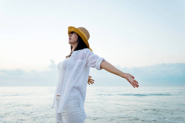 istock Young woman standing on beach with arms outstretched 1219749443