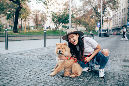 Young woman walking the streets of the city with her dog.
