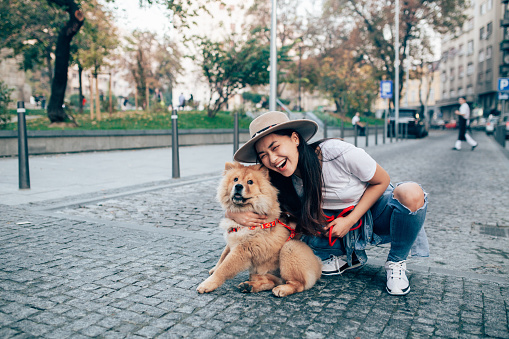 Young woman walking the streets of the city with her dog.