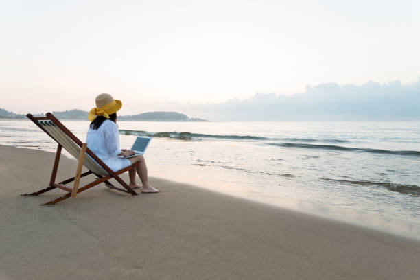 istock Woman using laptop at the beach 1219749767