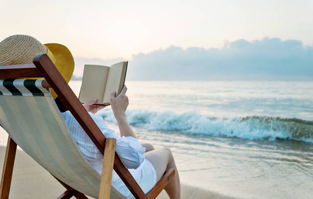 istock Woman reading book at the beach 1219750944