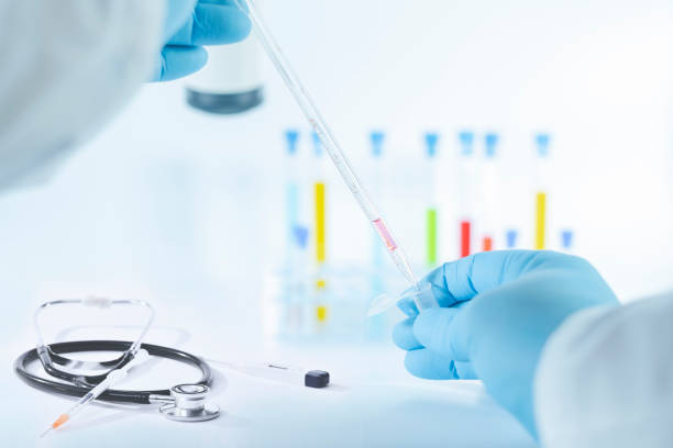 istock Hands in gloves using a graduated glass pipette 1219751295