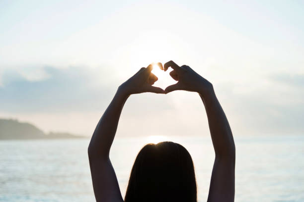 istock Woman hand making heart shape around the sun 1219751347