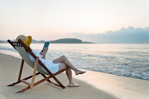 Woman using digital tablet at the beach.