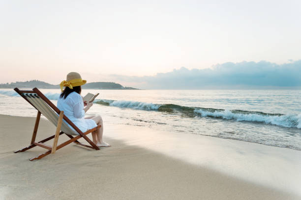 istock Woman reading book at the beach 1219752471