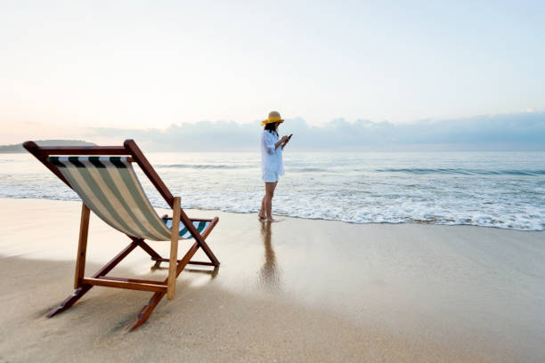 istock Woman using smart phone at the beach 1219752556