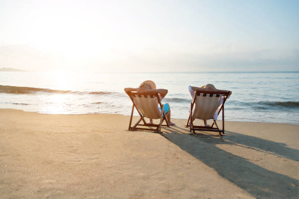 istock Couple sitting on deck chair at beach 1219752561