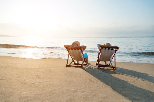 Portrait of a handsome man lying on a deckchair and resting. Happy mature man next to  the beach on Aegean sea. Summer vacation concept.