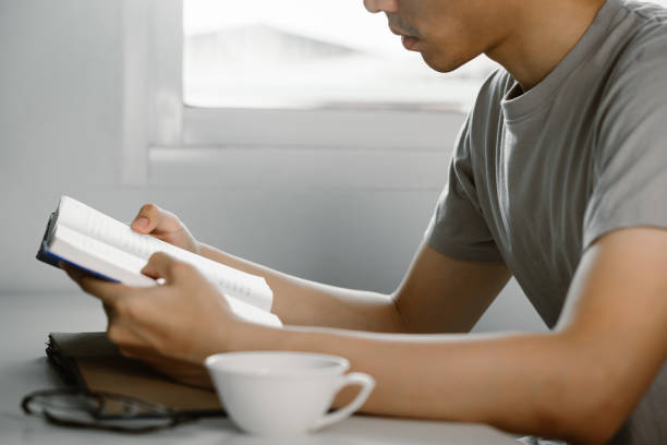 istock Young man reading book at work desk in free time from working at home, Knowledge and learning concept 1219755137