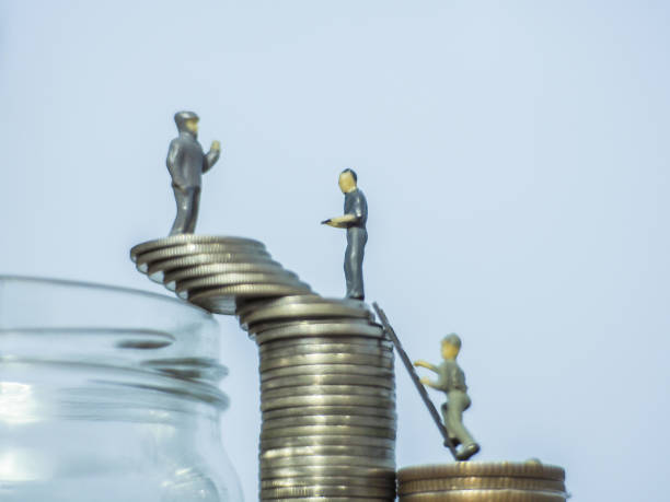 istock Miniature people standing on coins.and work on coins 1219755164