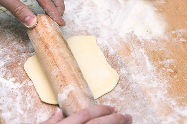 istock Hands baking dough with rolling pin on a wooden table. Cooking homemade cakes. 1219756306