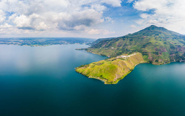 Aerial: lake Toba and Samosir Island view from above Sumatra Indonesia. Huge volcanic caldera covered by water, traditional Batak villages, green rice paddies, equatorial forest. Aerial: lake Toba and Samosir Island view from above Sumatra Indonesia. Huge volcanic caldera covered by water, traditional Batak villages, green rice paddies, equatorial forest. lake toba indonesia stock pictures, royalty-free photos & images