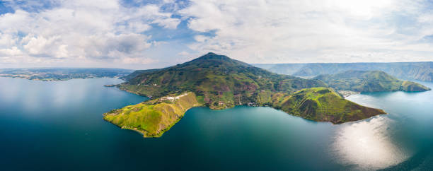 Aerial: lake Toba and Samosir Island view from above Sumatra Indonesia. Huge volcanic caldera covered by water, traditional Batak villages, green rice paddies, equatorial forest. Aerial: lake Toba and Samosir Island view from above Sumatra Indonesia. Huge volcanic caldera covered by water, traditional Batak villages, green rice paddies, equatorial forest. lake toba indonesia stock pictures, royalty-free photos & images