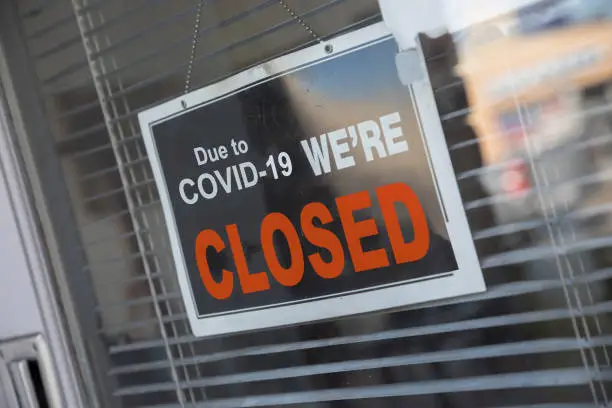 Store Temporarily Closed sign taped to the store's glass wall due to coronavirus pandemic.