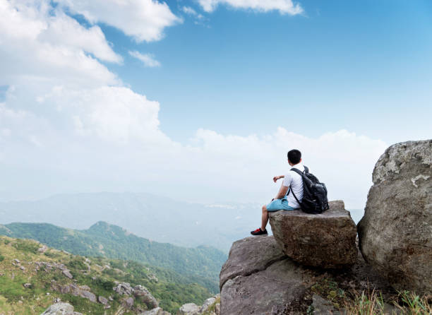 istock Man backpacker sitting on the top of mountain 1219763559