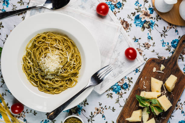 istock Pasta spaghetti with pesto sauce, basil, cherry-tomatoes, garlic and thyme in a white plate on old flowered table, top view 1219763907