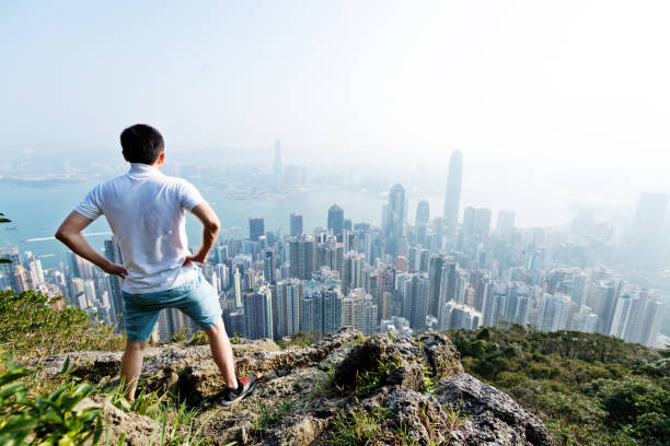 homens em pé no topo da montanha e olhando paisagem urbana - men on top of climbing mountain - fotografias e filmes do acervo