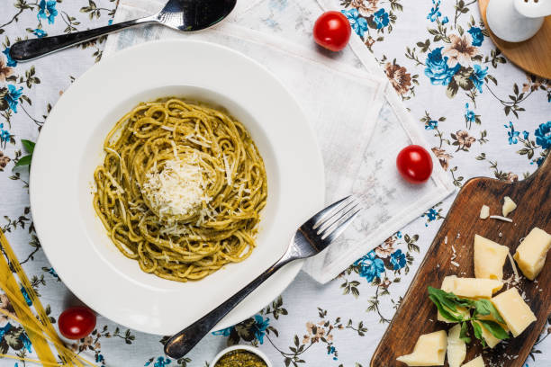 istock Pasta spaghetti with pesto sauce, basil, cherry-tomatoes, garlic and thyme in a white plate on old flowered table, top view 1219764499