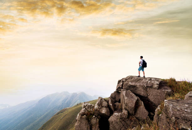 istock Man backpacker on the top of mountain at sunset 1219766437