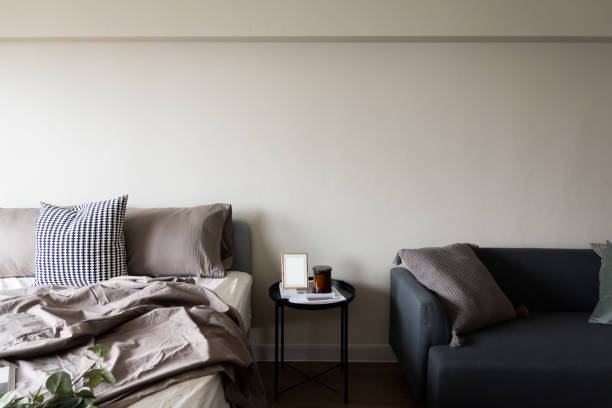 istock Bedroom corner grey velvet bed with soft pillows setting decorated with circular metal night table and beige painted wall in the background / cozy interior design 1219767049