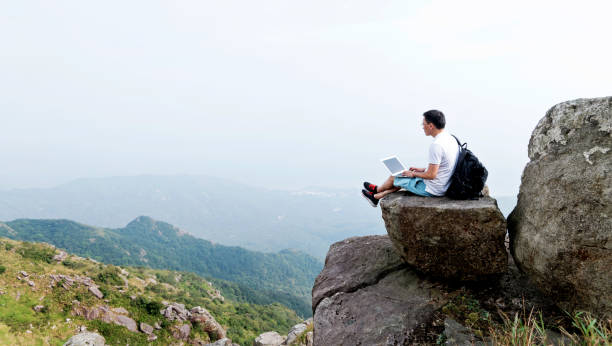istock Man using laptop on top of mountain 1219768469
