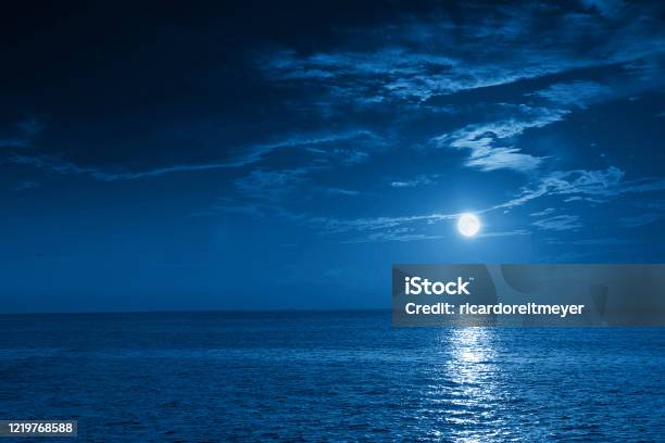 Bright Full Blue Moon Rises Over A Calm Ocean View Stock Photo - Download Image Now - Night, Sky, Sea