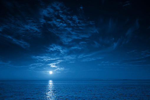 Brillante luna azul llena se eleva sobre una vista tranquila del océano photo