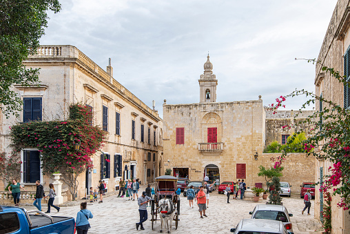 People walking in a small town square at Mdina city in the Republic of Malta.