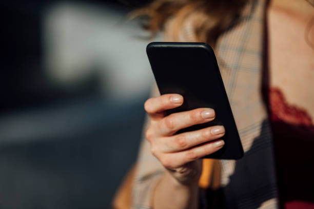 istock Online on the Go: Woman Using a Smartphone on the Street 1219772223