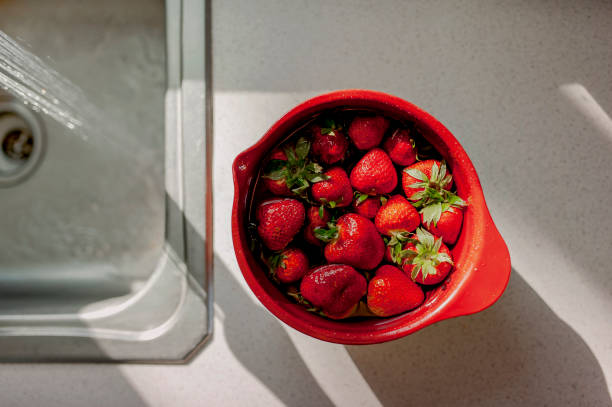 달리는 싱크대 옆에 물에 떠있는 딸기 그릇 - washing fruit preparing food strawberry 뉴스 사진 이미지