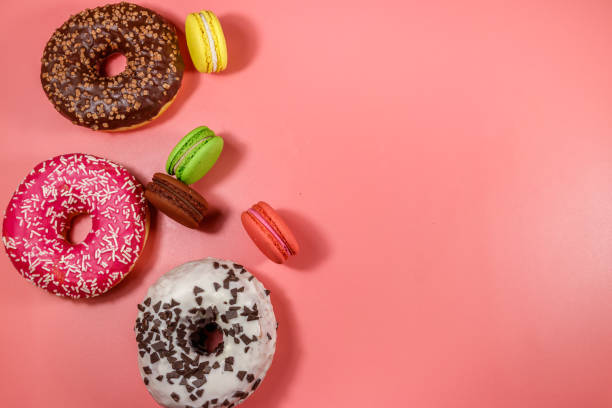 istock Tasty donuts and macaroons on pink background. Top view, copy space 1219774157