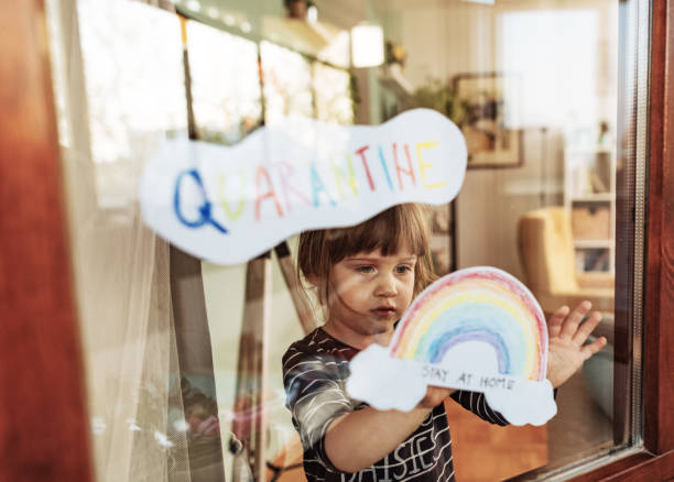 istock Three year old girl in quarantine putting supportive stickers on windows 1219774394
