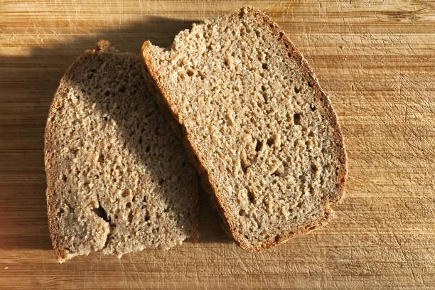 Two slices of rye bread lying on a wooden cutting Board.