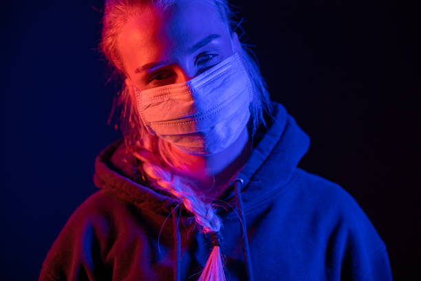 istock Exhausted or sick woman in protective face mask with multi colored lights 1219774442