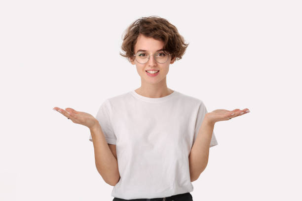 clueless young woman in a white shirt and eyeglasses shrugging shoulders being at loss. - blank expression head and shoulders horizontal studio shot imagens e fotografias de stock