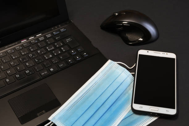 istock Surgical face blue masks for coronavirus, covid-19 protection on notebook keyboard with mouse and smartphone. work stay home. concept of smart working. 1219778086