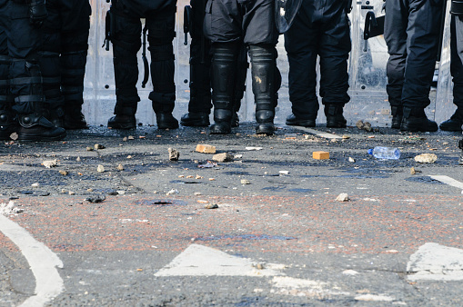 Stones and bricks litter the road as police riot squad move forward