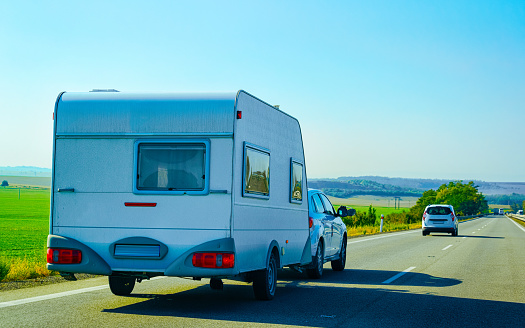 Vacation trip with Car with Caravan trailer on road of Slovenia. Auto and Camper carrier while Summer drive on highway. Holiday journey in rv motorhome on hauler. Motor home minivan motion ride