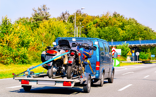 Vacation trip with Caravan Car and trailer with motorcycles on road of Italy. Camper and Summer drive on highway. Holiday journey in rv motorhome for recreation. Motor home motion ride.