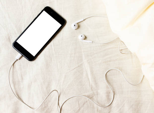 istock Smartphone with headphones top view in rumpled bed close-up 1219786851