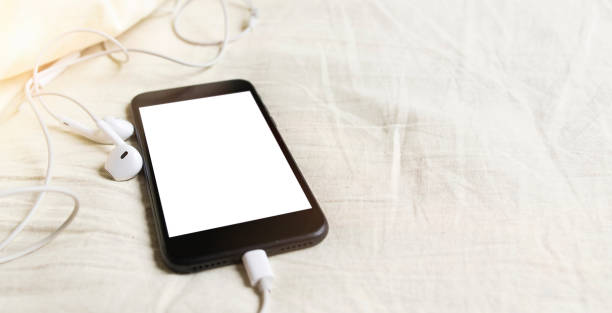 istock Smartphone with headphones top view in rumpled bed close-up 1219787011