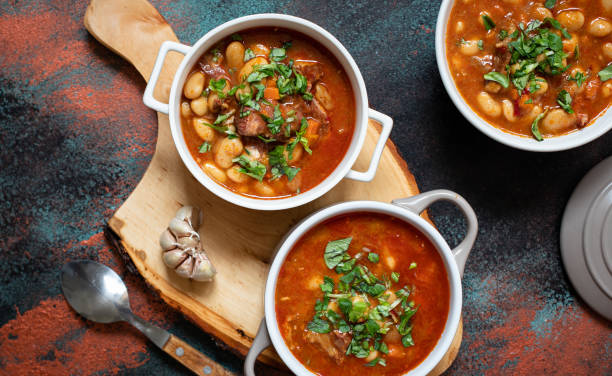 istock Bean soup with meat and vegetables served on a rustic board with garlic. Traditional Balkan soup or stew Corbast Pasulj (Grah). Top view, copy space 1219787247