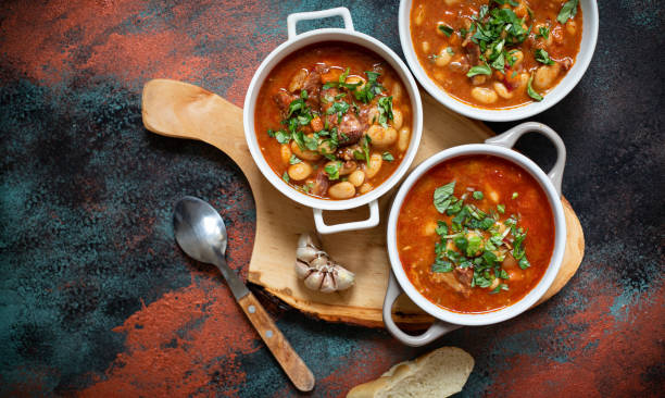 istock Bean soup with meat and vegetables served on a rustic board with garlic. Traditional Balkan soup or stew Corbast Pasulj (Grah). Top view, copy space 1219787261
