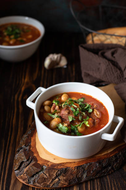 istock Bean soup with meat and vegetables served on a rustic board and wooden table with bread and garlic. Traditional Balkan soup Pasulj (Grah). Close-up, selective focus 1219787272