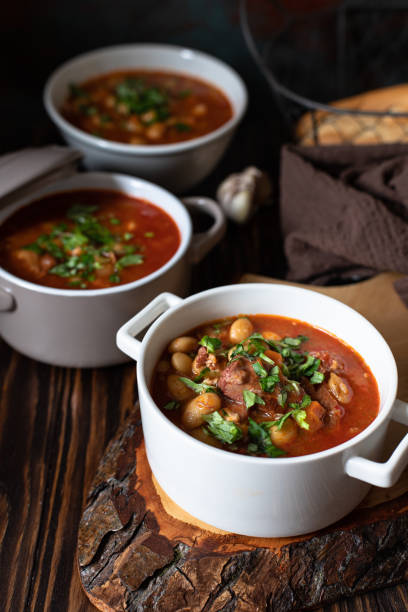 istock Bean soup with meat and vegetables served on a rustic board and wooden table with bread and garlic. Traditional Balkan soup Pasulj (Grah). Close-up, selective focus 1219787284