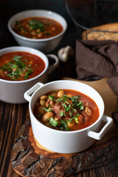istock Bean soup with meat and vegetables served on a rustic board and wooden table with bread and garlic. Traditional Balkan soup Pasulj (Grah). Close-up, selective focus 1219787293
