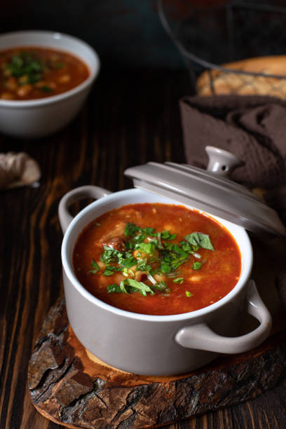 istock Bean soup with meat and vegetables served on a rustic board and wooden table with bread and garlic. Traditional Balkan soup Pasulj (Grah). Close-up, selective focus 1219787296
